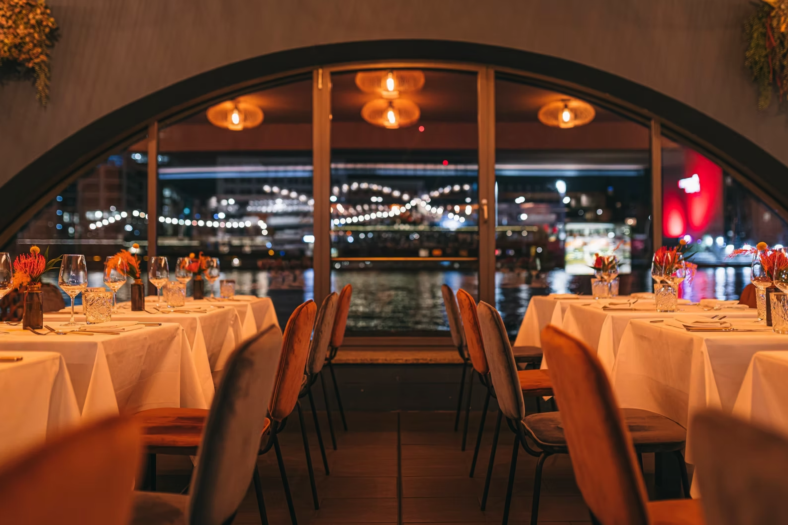 RIVO – Dinner-Setting mit Bogenfenster und Blick auf die Spree bei Nacht