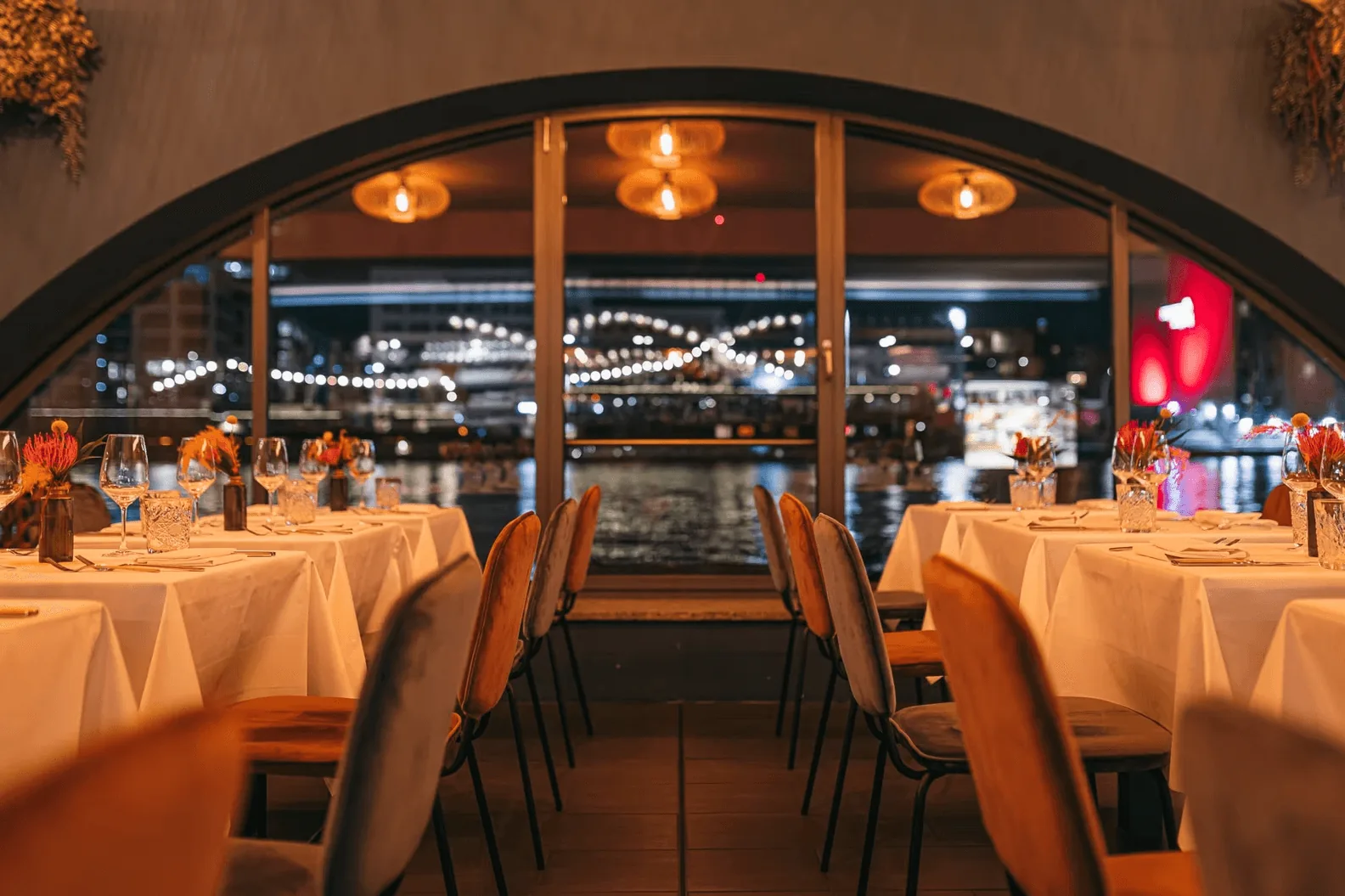 RIVO – Dinner-Setting mit Bogenfenster und Blick auf die Spree bei Nacht